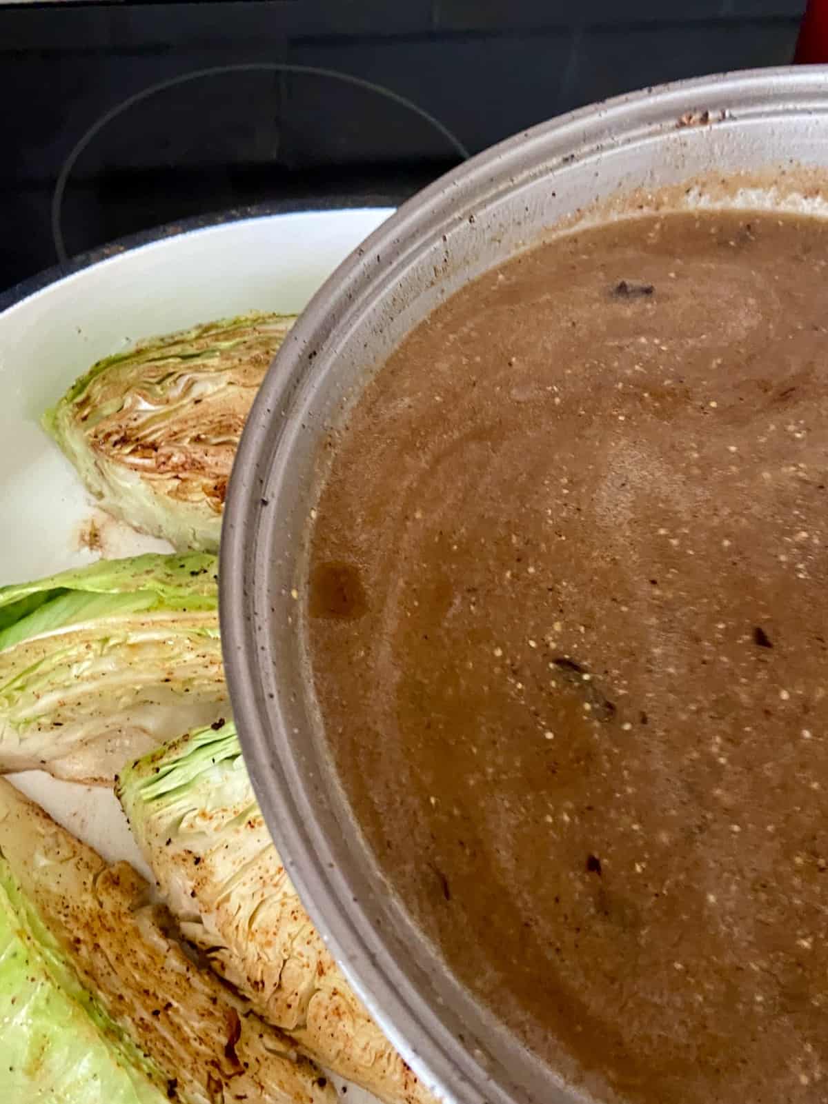 Braising liquid being poured over browned cabbage wedges.