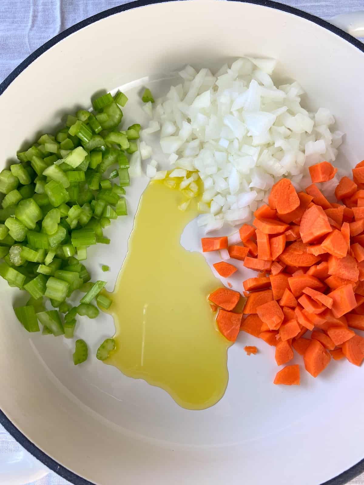 Oil, chopped carrots, chopped celery and chopped onions in white dutch oven.