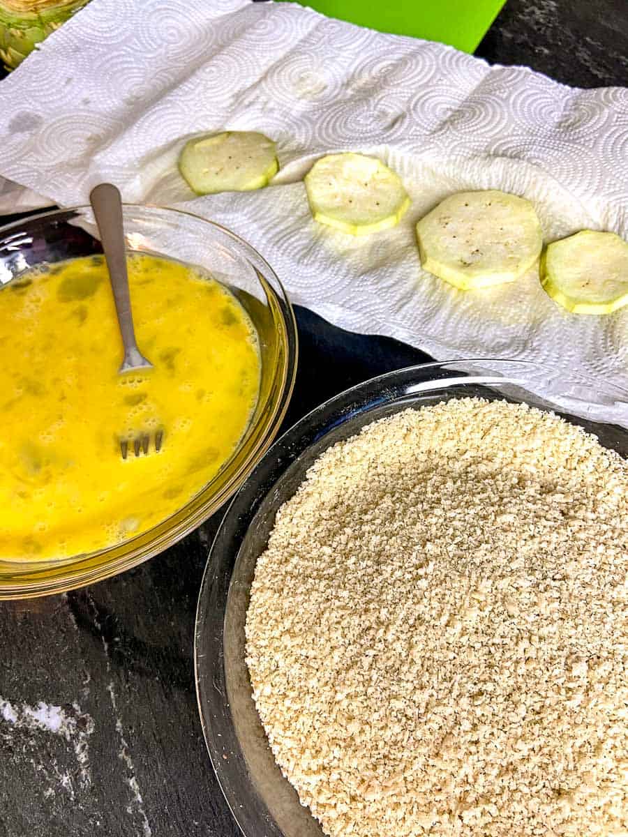 Bowl of beaten eggs and a bowl of seasoned bread crumbs on counter