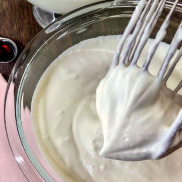 Whipped cream in a stiff peak on wire whisk