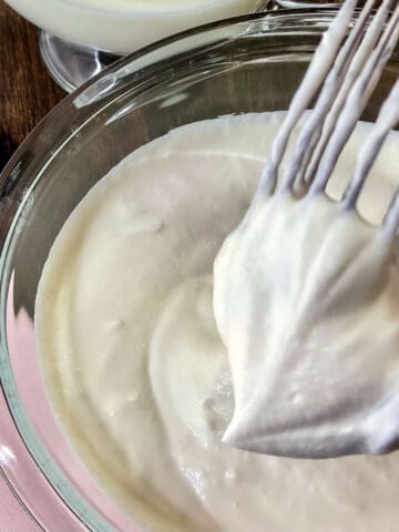 Whipped cream in a stiff peak on wire whisk