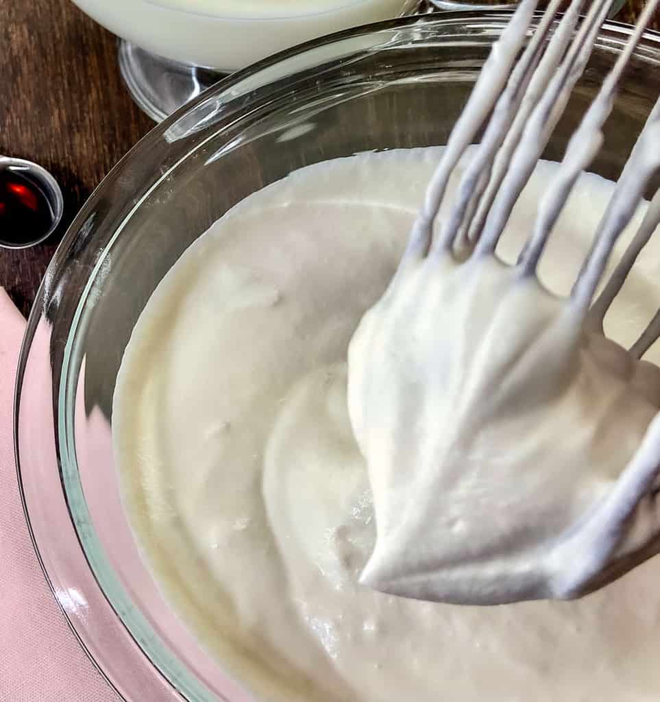 Whipped cream in a stiff peak on wire whisk