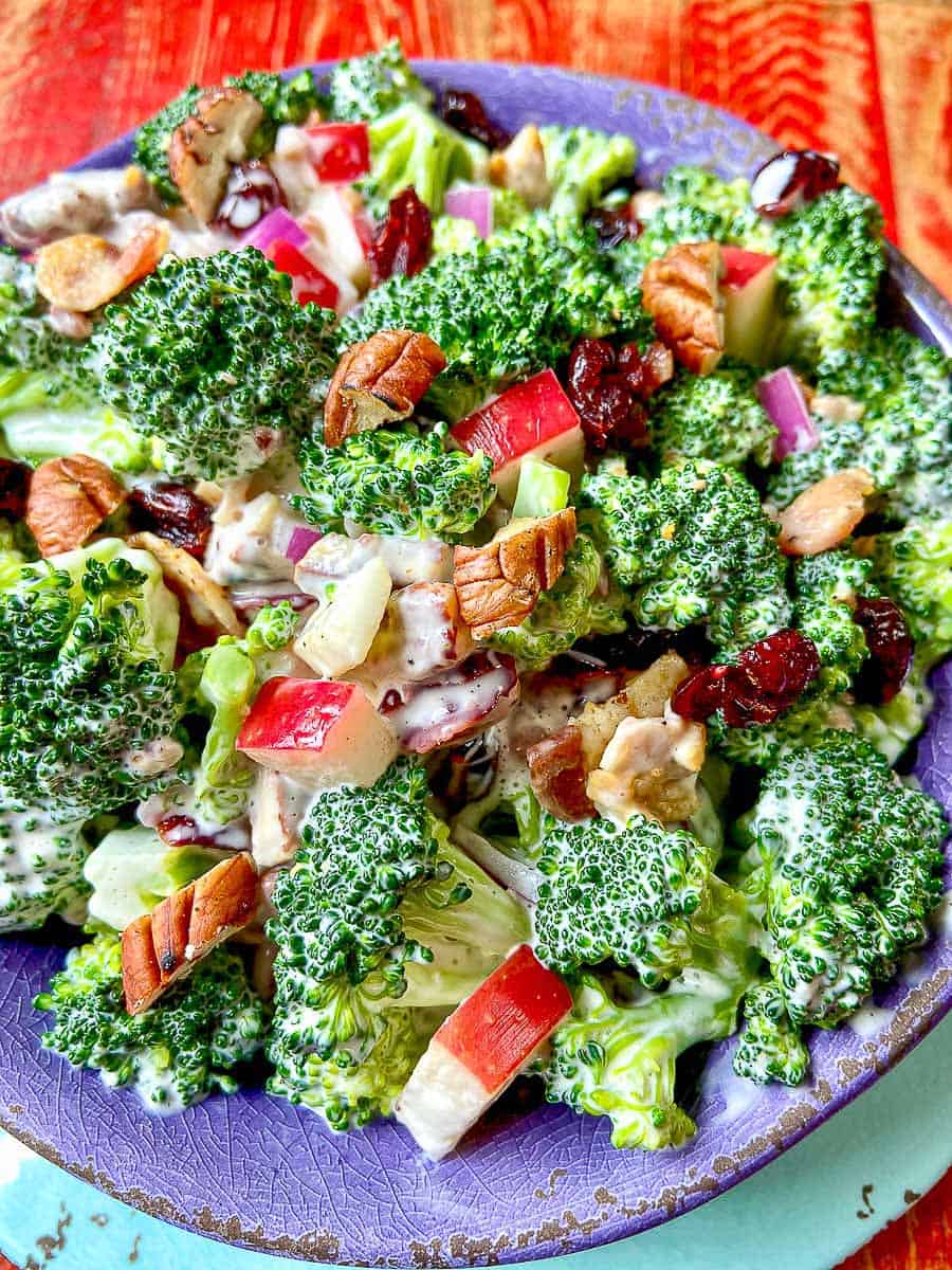 Broccoli salad in purple bowl on red wooden table