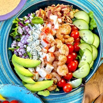 Seafood Cobb Salad with ingredients in rows on top of mixed greens