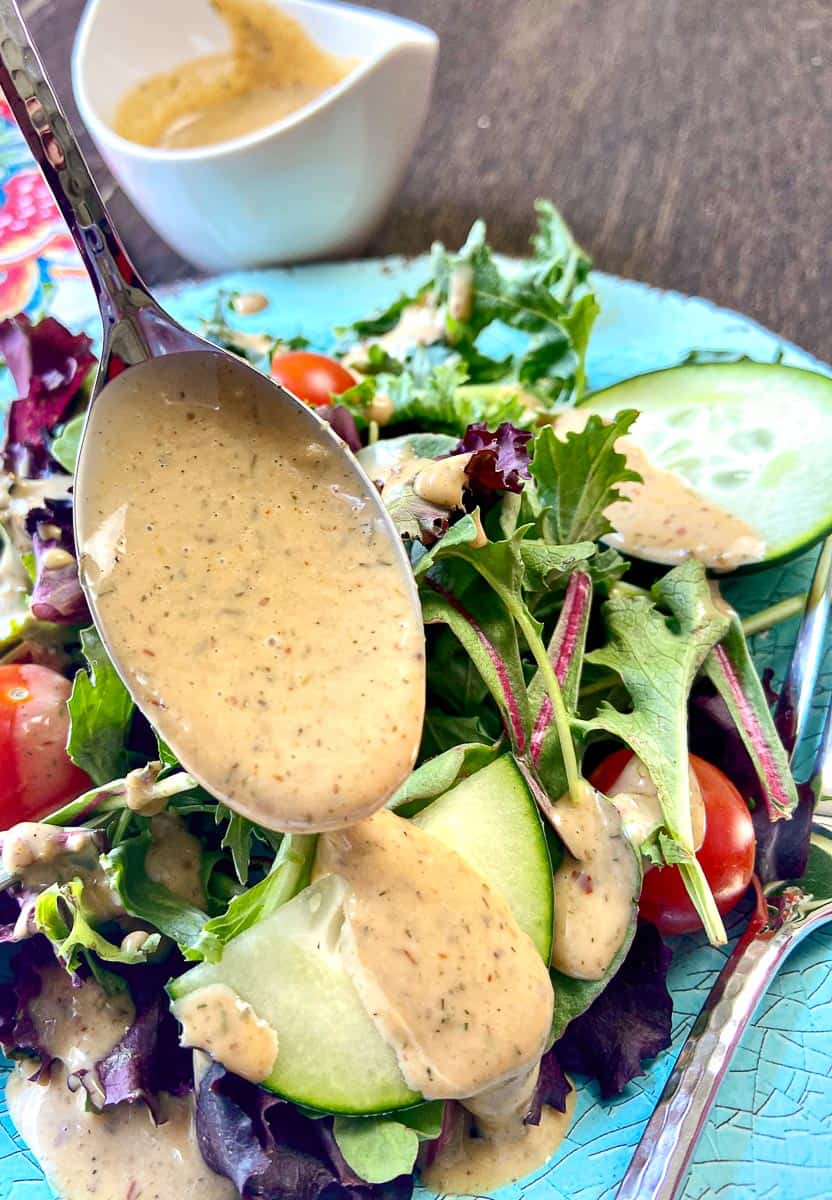 Remoulade salad dressing being drizzled over salad