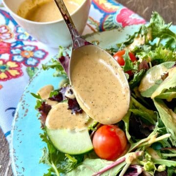 Louisiana Remoulade Sauce being drizzled over a mixed green salad