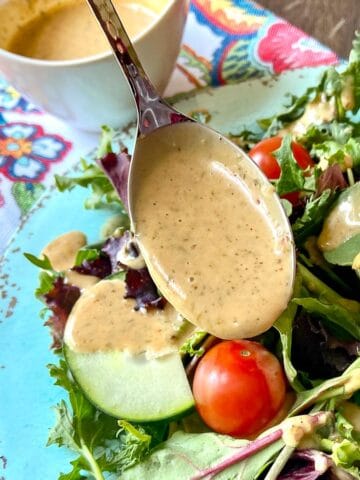 Louisiana Remoulade Sauce being drizzled over a mixed green salad