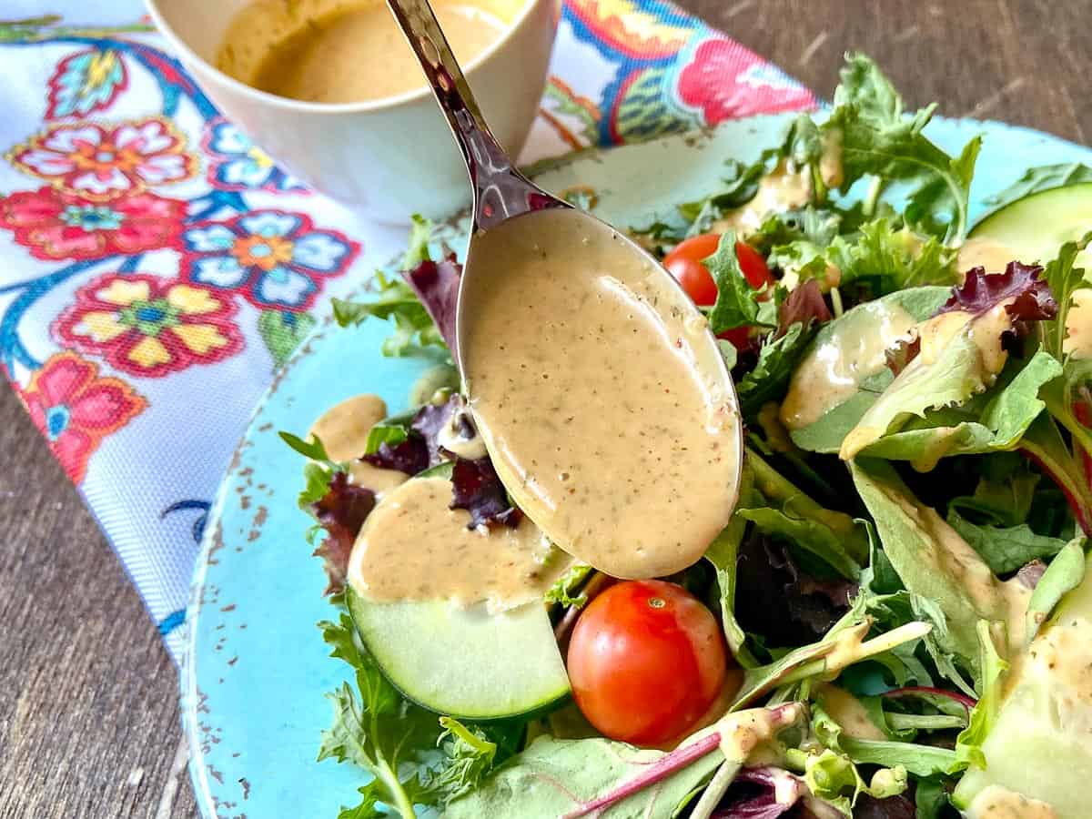 Louisiana Remoulade Sauce being drizzled over a mixed green salad