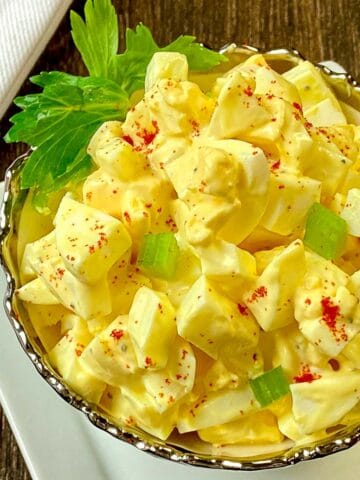 Close up of egg salad in decorative silver and white bowl.