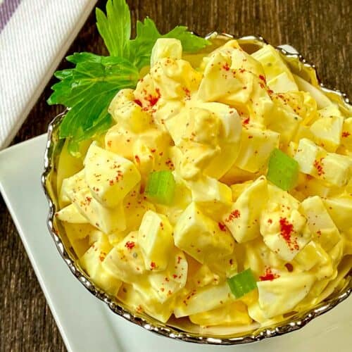 Close up of egg salad in decorative silver and white bowl.