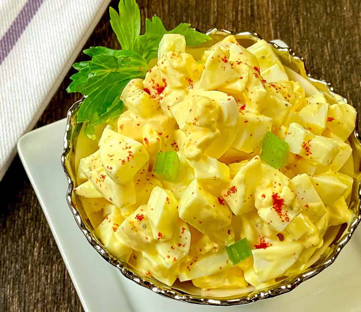 Close up of egg salad in decorative silver and white bowl.