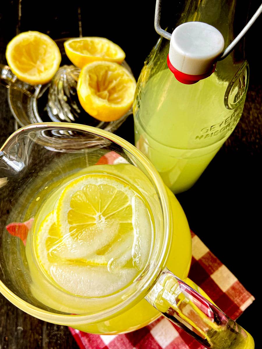 Lemonade in pitcher garnished with ice cubes and lemon slices.