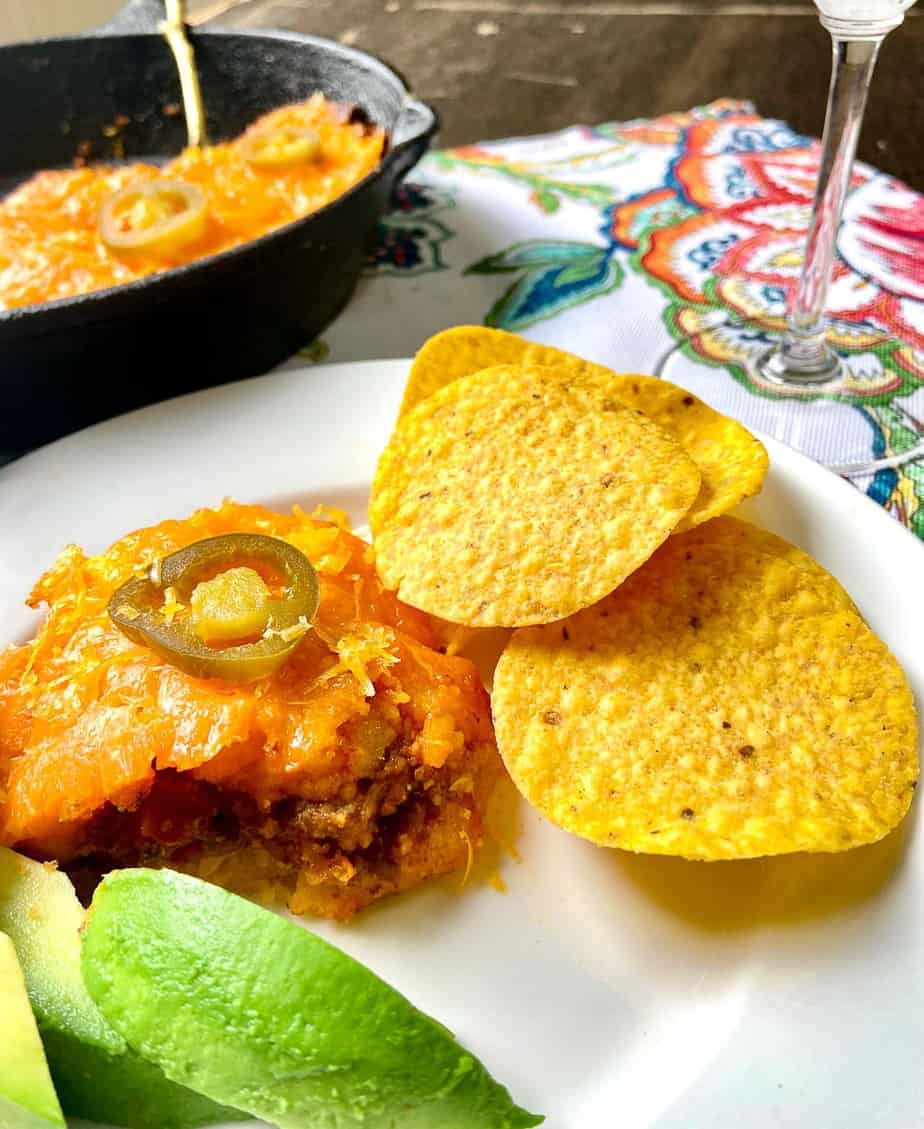 Tamale pie on plate with tortilla chips and avocado.