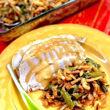 Green Bean casserole on gold plate with turkey and gravy.