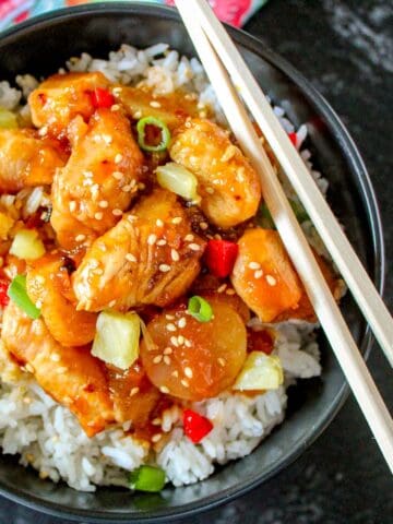 Sweet and sour shrimp in black bowl.