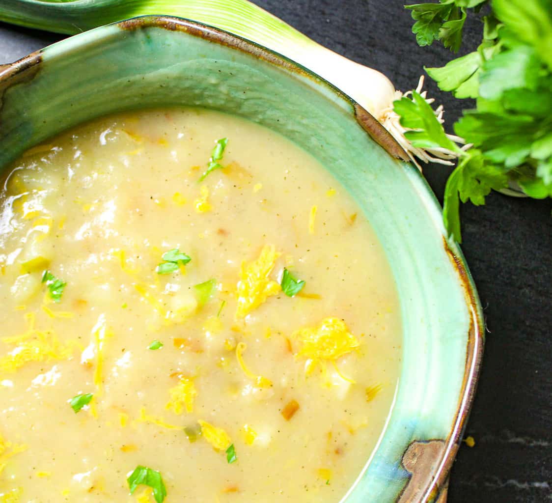 Vegan potato leek soup in greeen bowl garnished with parsley.