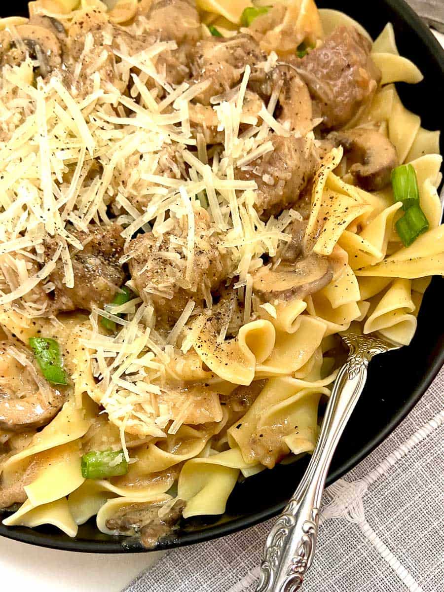 Beef stroganoff garnished with shredded parmesan cheese.