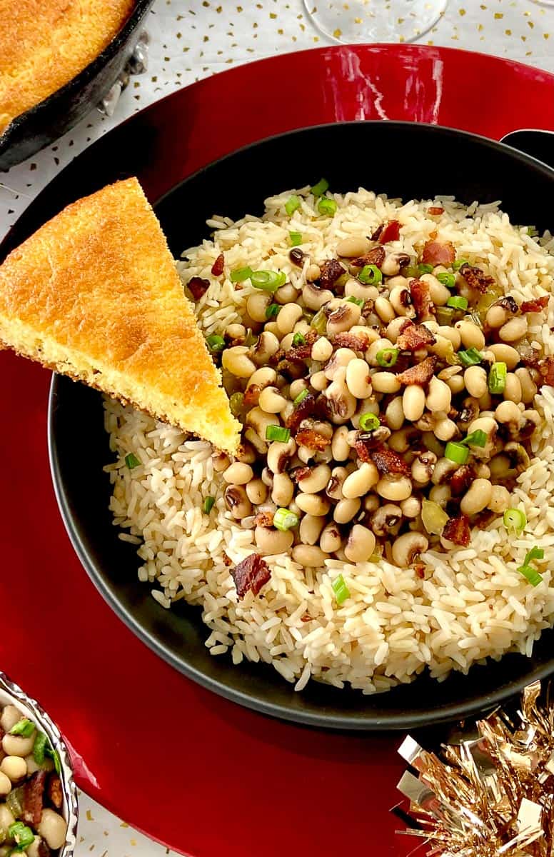 Hoppin' John in black bowl with slice of cornbread.
