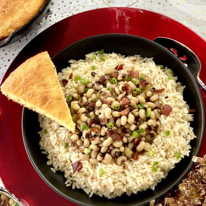 Hoppin john in black bowl with slice of cornbread.