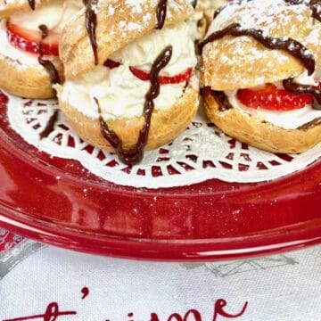 Cream puffs on red plate.