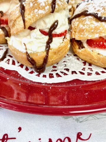 Cream puffs on red plate.