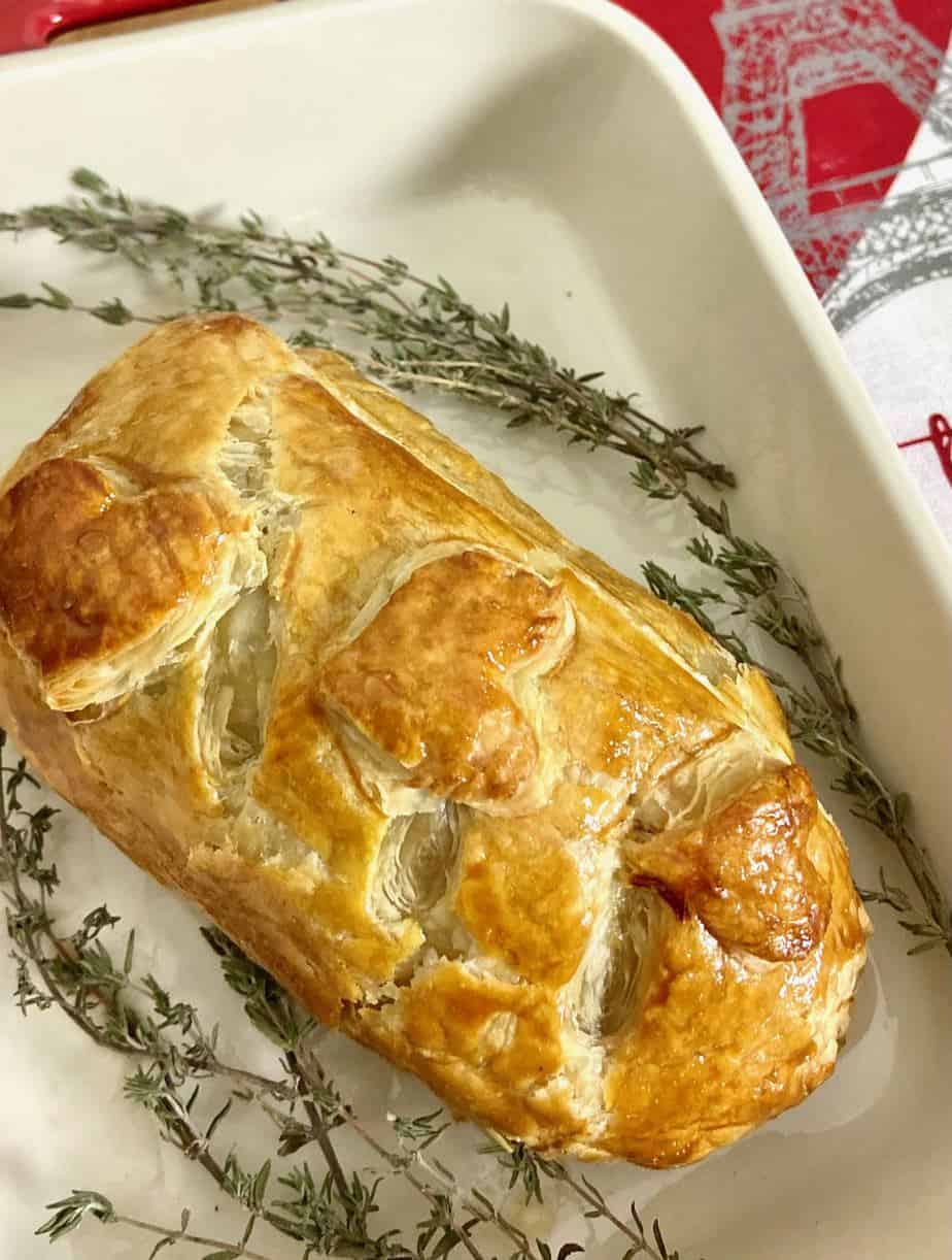 Golden brown baked Beef Wellington garnished with thyme sprigs.