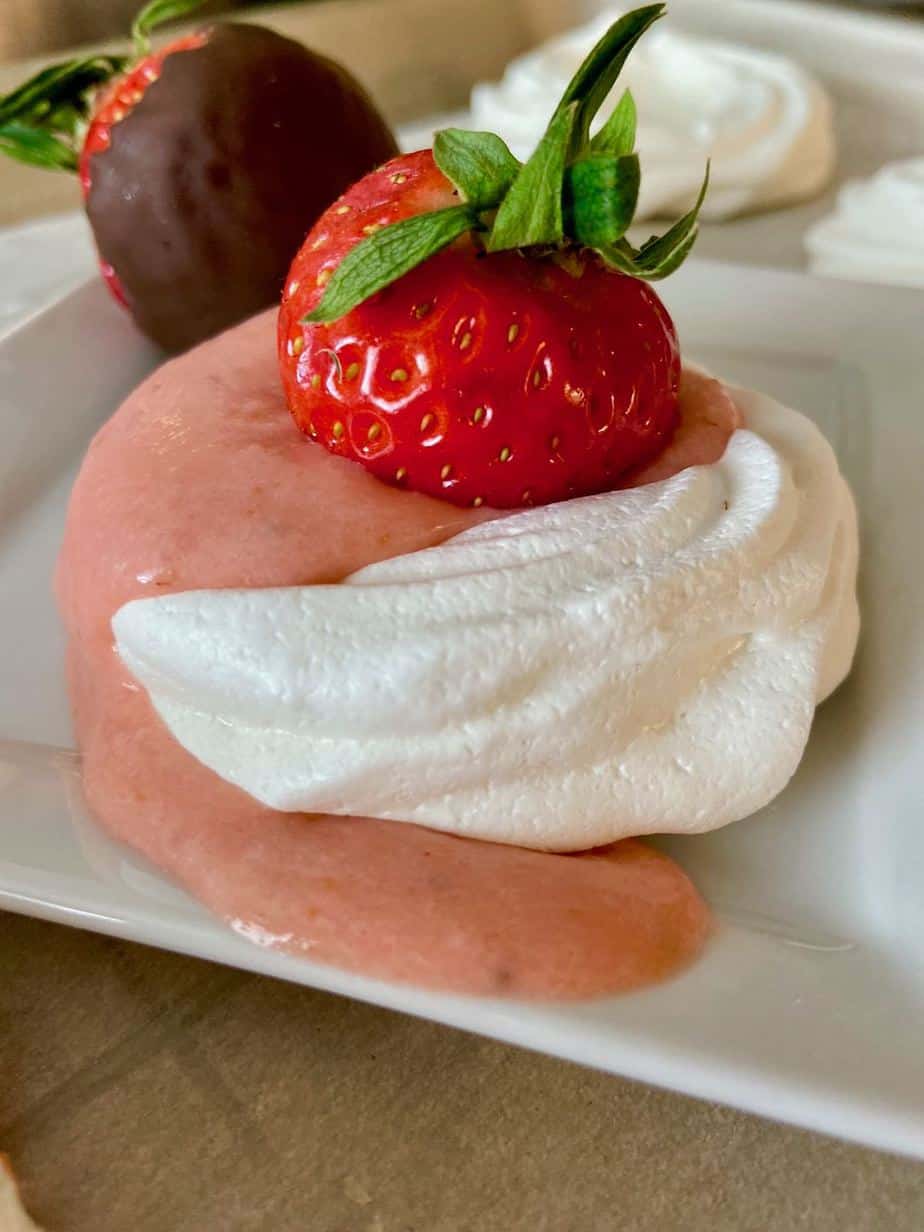 Mini pavlova with strawberry on plate.