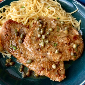 Veal Scallopini with a side of pasta on a blue plate.