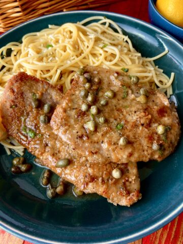 Veal Scallopini with a side of pasta on a blue plate.