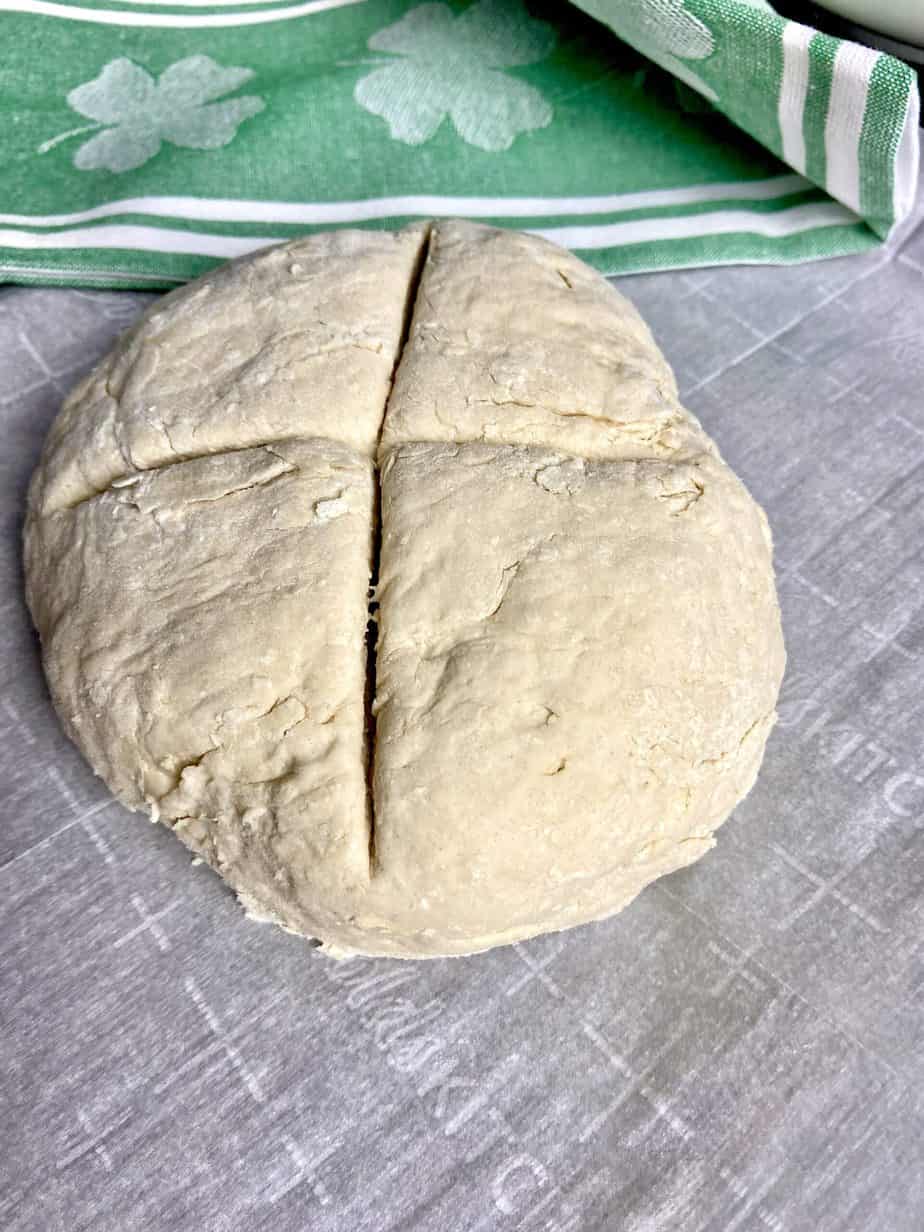 Round disc of dough scored with an X on top.