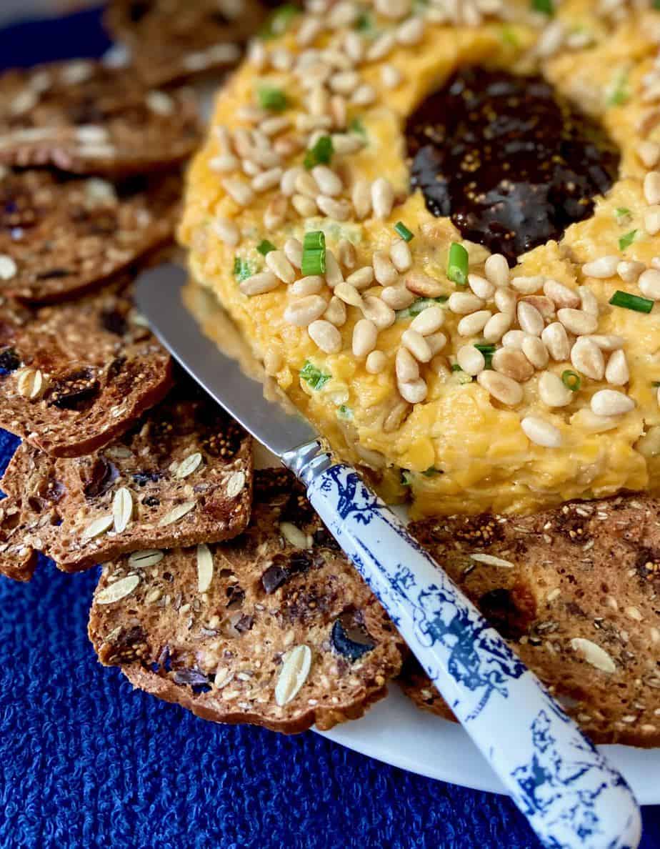 Cheddar cheese ring garnished with pine nuts served with crackers.