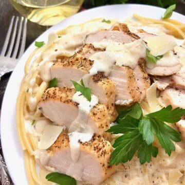 Chicken Linguine Alfredo on white plate garnished with flat leaf parsley.
