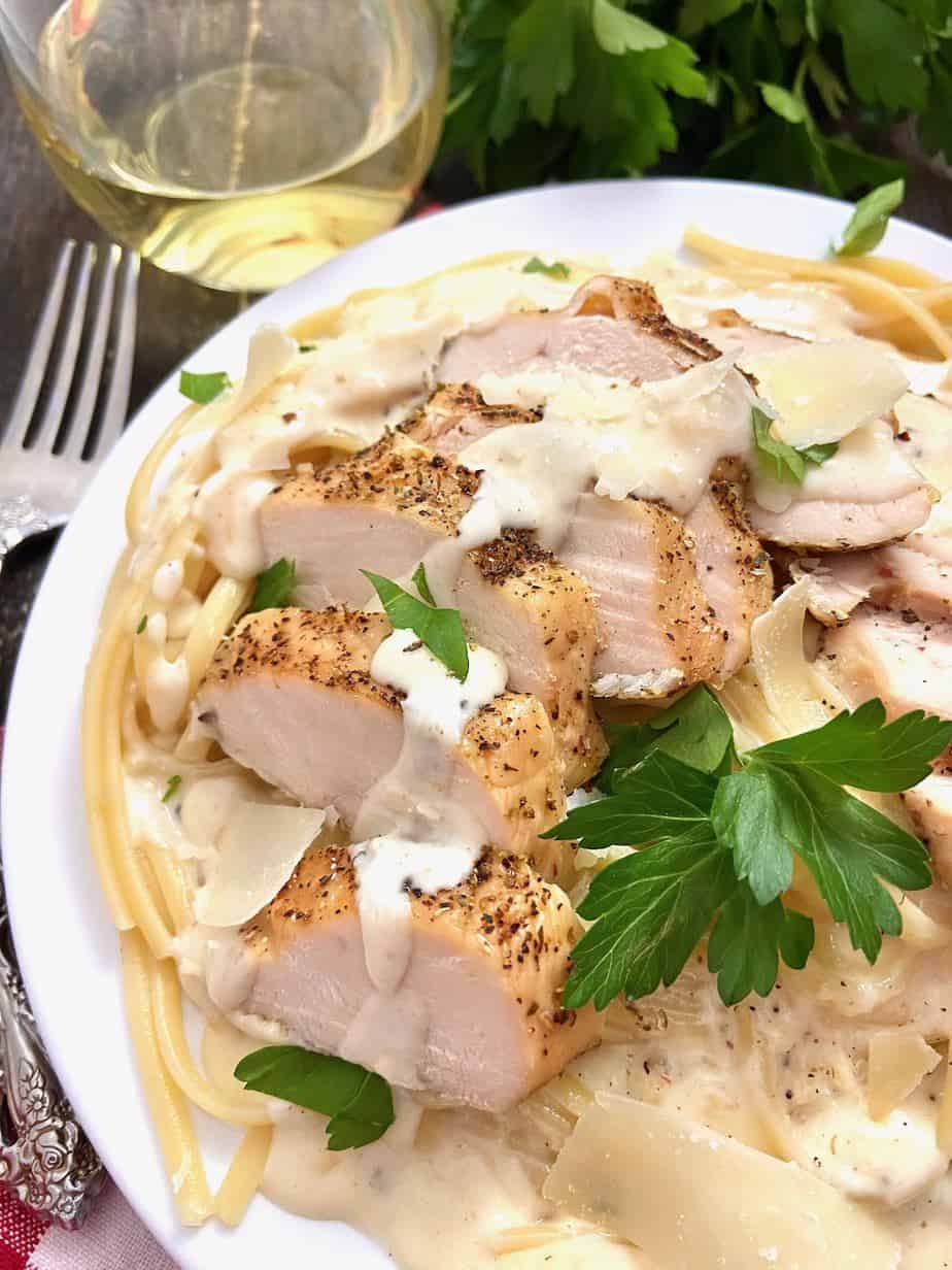 Chicken Linguine Alfredo on white plate garnished with flat leaf parsley.