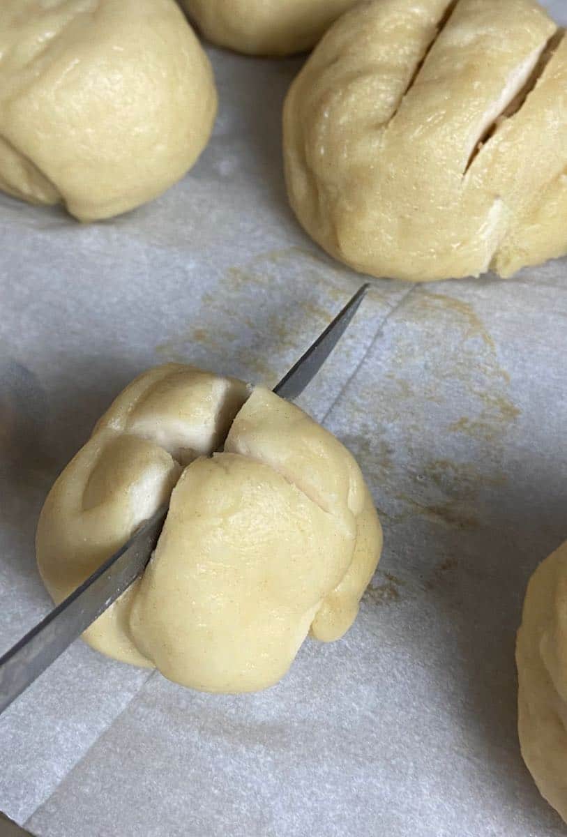 Dough being scored with sharp knife.