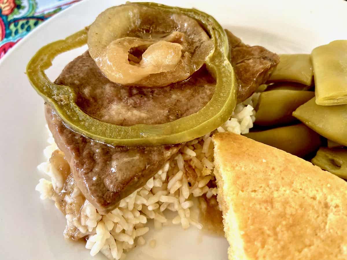 Smothered steak topped with sauteed onion and bell pepper slices.