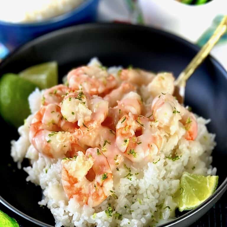 Creamy coconut shrimp and rice in black bowl.