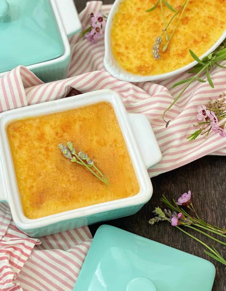 Creme brulee in square turquoise ramekin with sprigs of lavender on top.