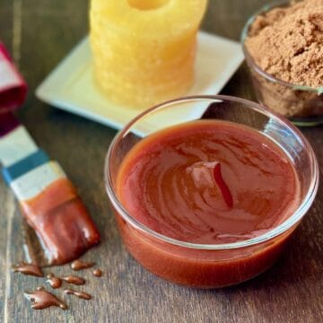 Sauce in glass bowl on brown table.