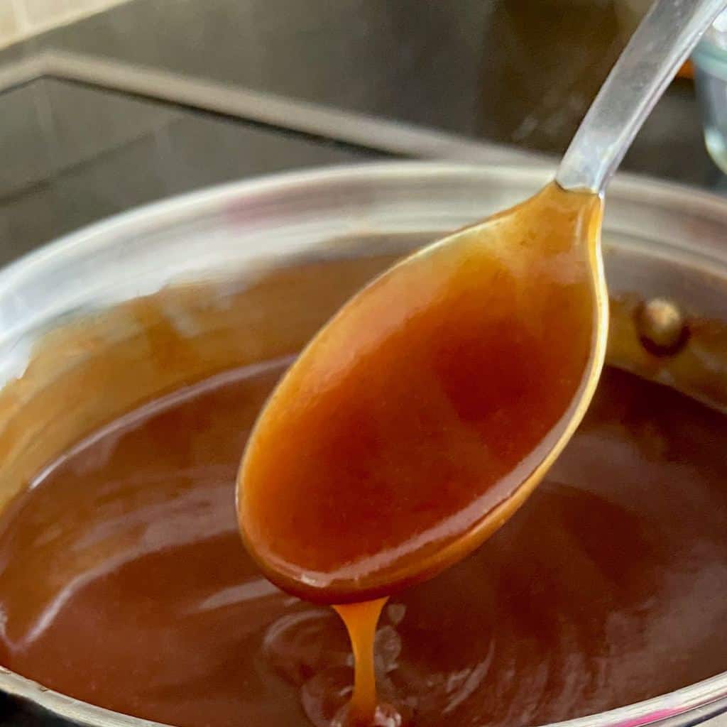 Sauce dripping from a spoon over the saucepan.