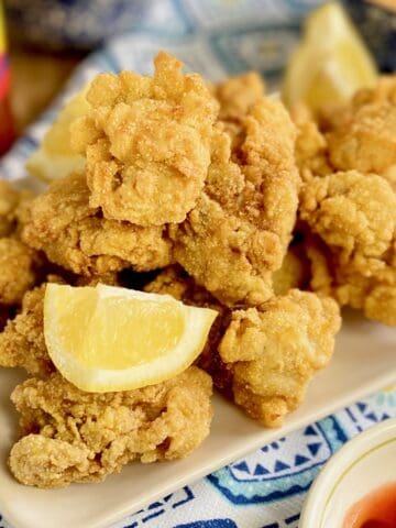 Fried oysters on platter with lemon wedges.