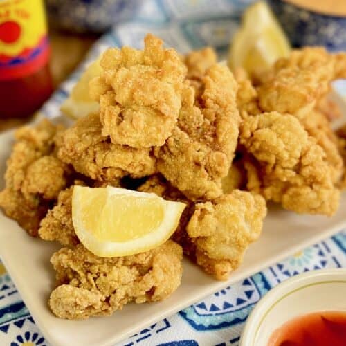 Fried oysters on platter with lemon wedges.