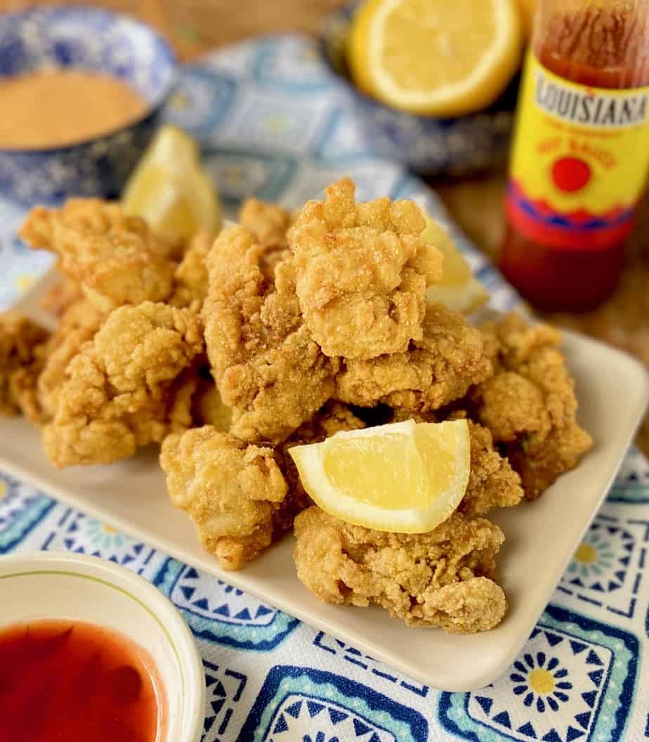 Southern Fried Oysters on a serving platter garnished with lemon slices.