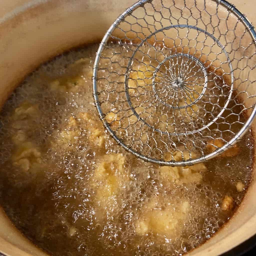 Oysters being fried in stockpot.