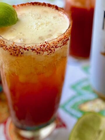 Close up of Michelada garnished with lime wedge.