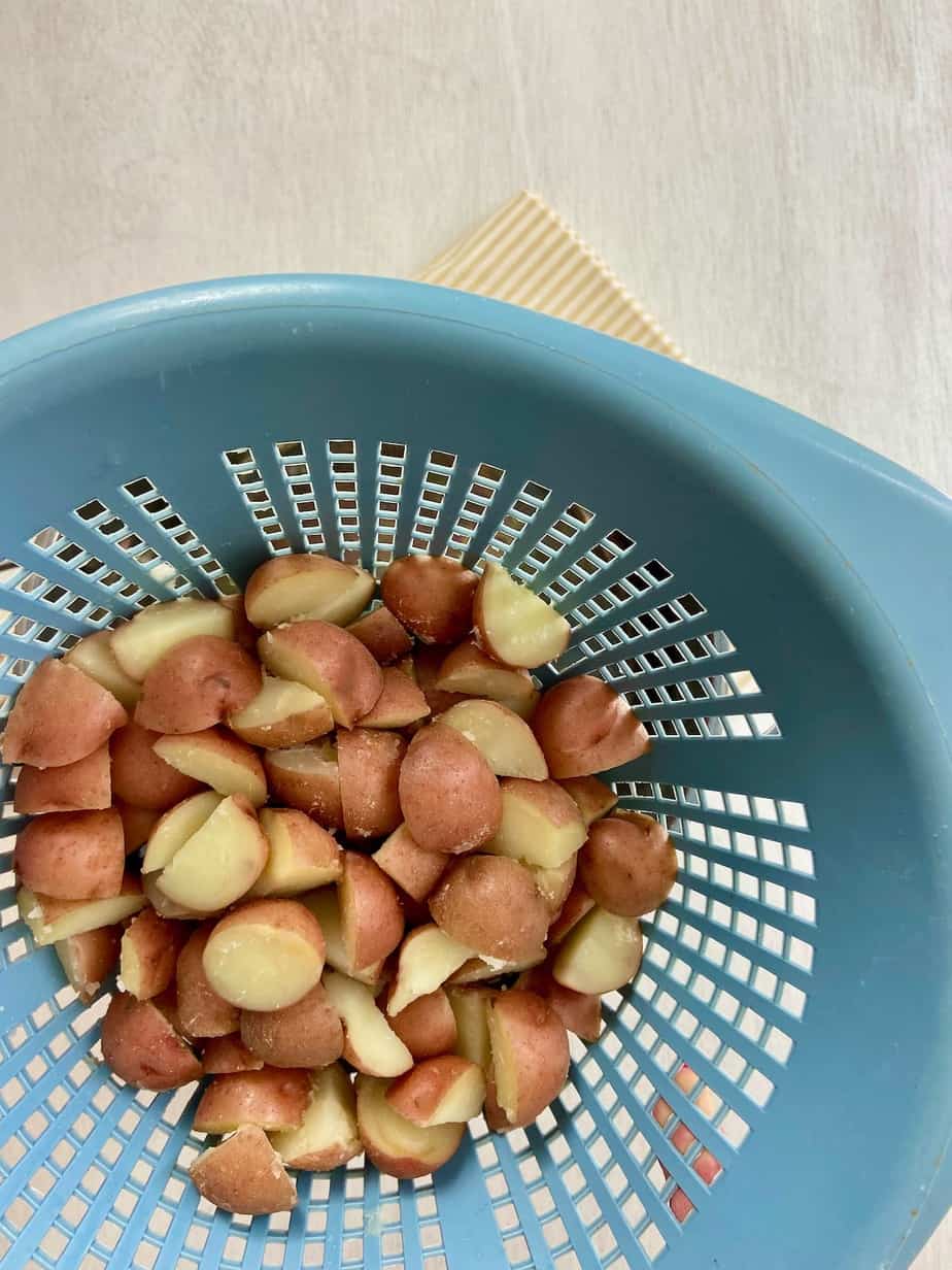 Cubed red potatoes in blue colander.