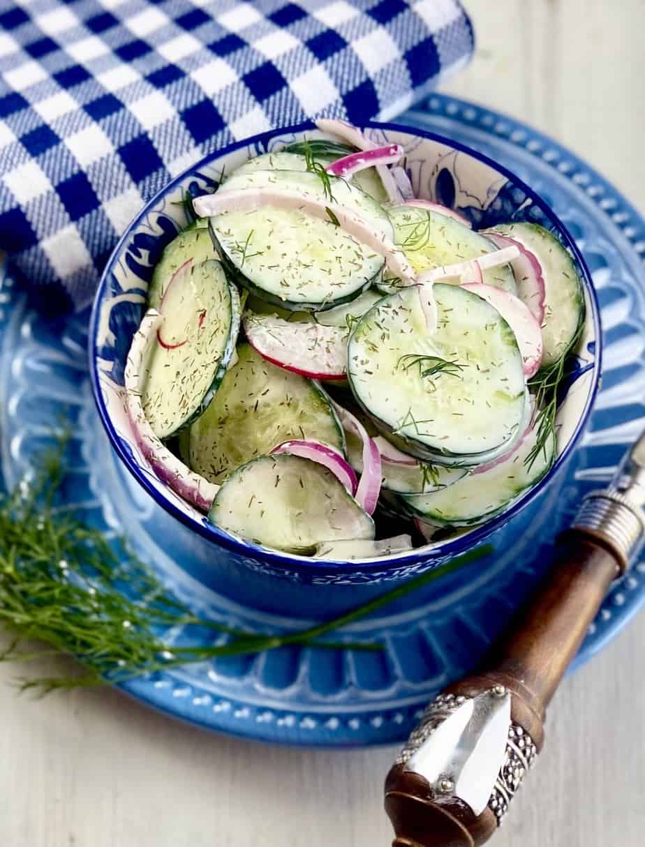Creamy cucumber salad in a blue and white bowl.