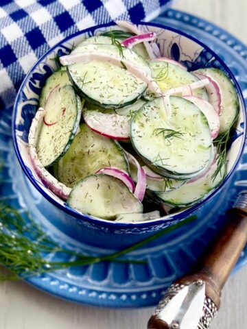 Creamy cucumber salad in a blue and white bowl.