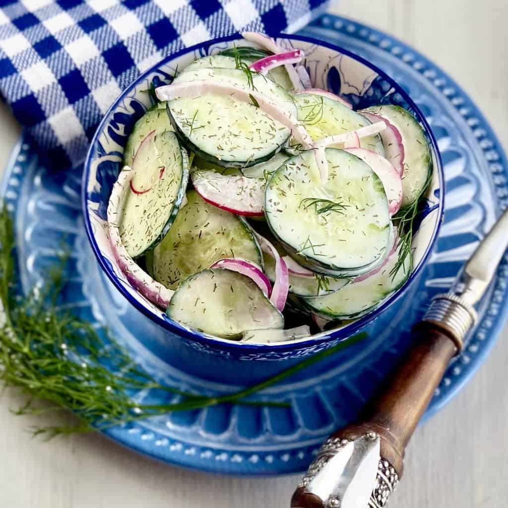 Creamy cucumber salad in a blue and white bowl.