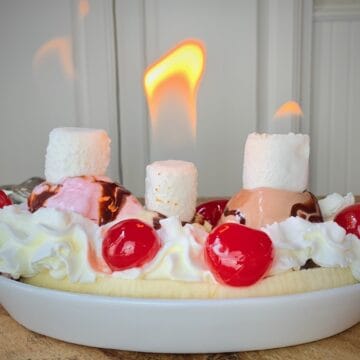 Flaming banana split in white dish.