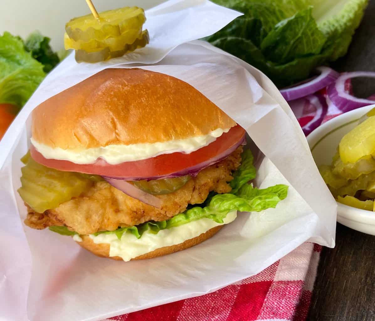 Fried chicken sandwich in white paper wrapper.